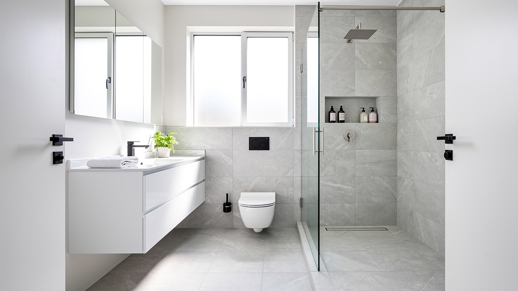 A modern, small bathroom with a floating vanity, wall-mounted toilet, and glass walk-in shower, demonstrating efficient design.